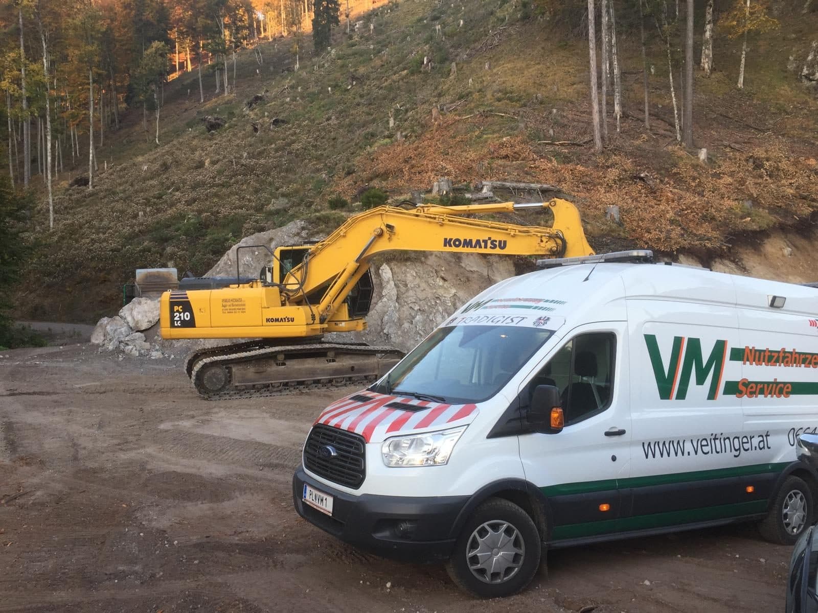 Serviceauto vor einem Bagger auf der Baustelle